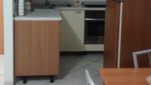 A kitchen with wooden cabinets, a white countertop, a yellow hanging light, and a refrigerator. - A new and welcoming seaside house near Taormina (Sant'Alessio Siculo)