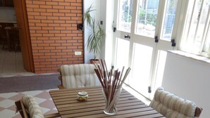 A wooden dining table with striped cushions, a small decorative bowl, and a glass vase with sticks. - A new and welcoming seaside house near Taormina (Sant'Alessio Siculo)