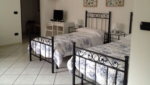 A bedroom with two beds, a desk, a television, and two wall-mounted lamps. - A new and welcoming seaside house near Taormina (Sant'Alessio Siculo)