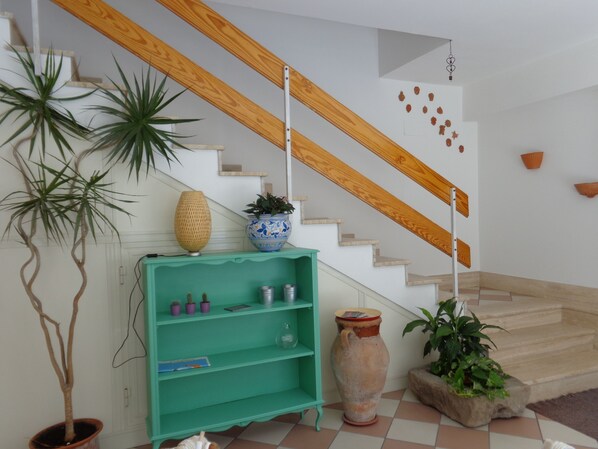 A staircase with wooden handrails, a green shelf with various items, and potted plants. - A new and welcoming seaside house near Taormina (Sant'Alessio Siculo)