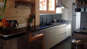 Una cocina moderna con armarios de madera, encimera negra, pileta de acero inoxidable y estufa integrada.
