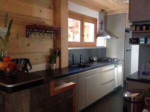 Una cucina moderna con mobili in legno, un piano di lavoro nero, un lavello in acciaio inossidabile e un piano cottura integrato.