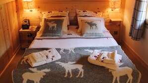 Una habitación cálida de cabaña de madera con una cama, dos mesitas de noche y una lámpara fijada a la pared.