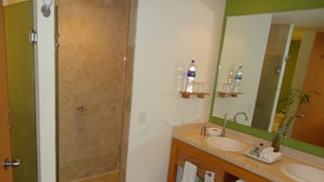 Une salle de bain avec une douche, deux lavabos, un miroir et un porte-serviettes.