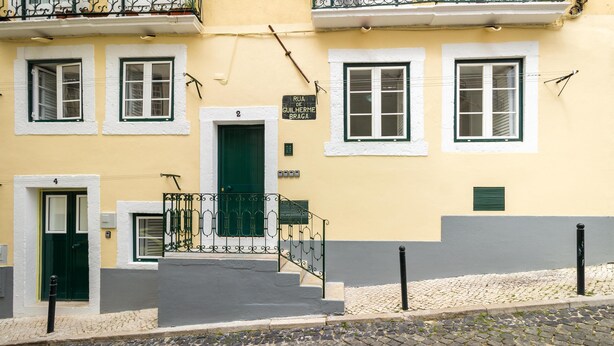 Rakennuksessa on vihreä ovi, valkoiset ikkunat ja kyltti, jossa lukee: ”Rua de Guilherme Braga”.