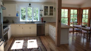 A spacious kitchen with white cabinets, a large island, and a dining area with wooden chairs.