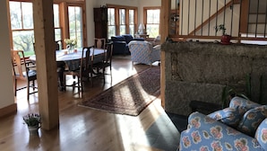 A spacious living area with a dining table, chairs, a sofa, and a staircase.