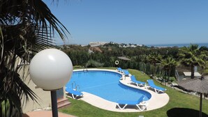 A swimming pool with blue water, surrounded by lounge chairs and palm trees. -  Marina de Casarès Dona Julia Golf Andalusia 29690 ES (Casarès costa-malaga andalousie)