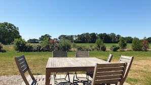 A wooden table and chairs set outdoors with a clear view of a field and trees in the background. - Le Pressoir: Spacious vacation rental, surrounded by nature, forest 50 meters away, Pornic 20 minutes away (Chaumes-En-Retz)