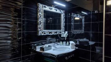 Une salle de bain moderne avec des carreaux de sol noirs et blancs formant un motif à damier, un lavabo blanc, un bidet et deux grands miroirs dotés de cadres décoratifs.