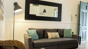 A grey sofa with patterned cushions, a floor lamp, and a mirror above it. - Located in the heart of Ponce; includes a restaurant, plazas, and two bedrooms. (Ponce Pueblo)