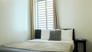 A simple, clean room with a bed, a nightstand, and a window with blinds. - Located in the heart of Ponce; includes a restaurant, plazas, and two bedrooms. (Ponce Pueblo)
