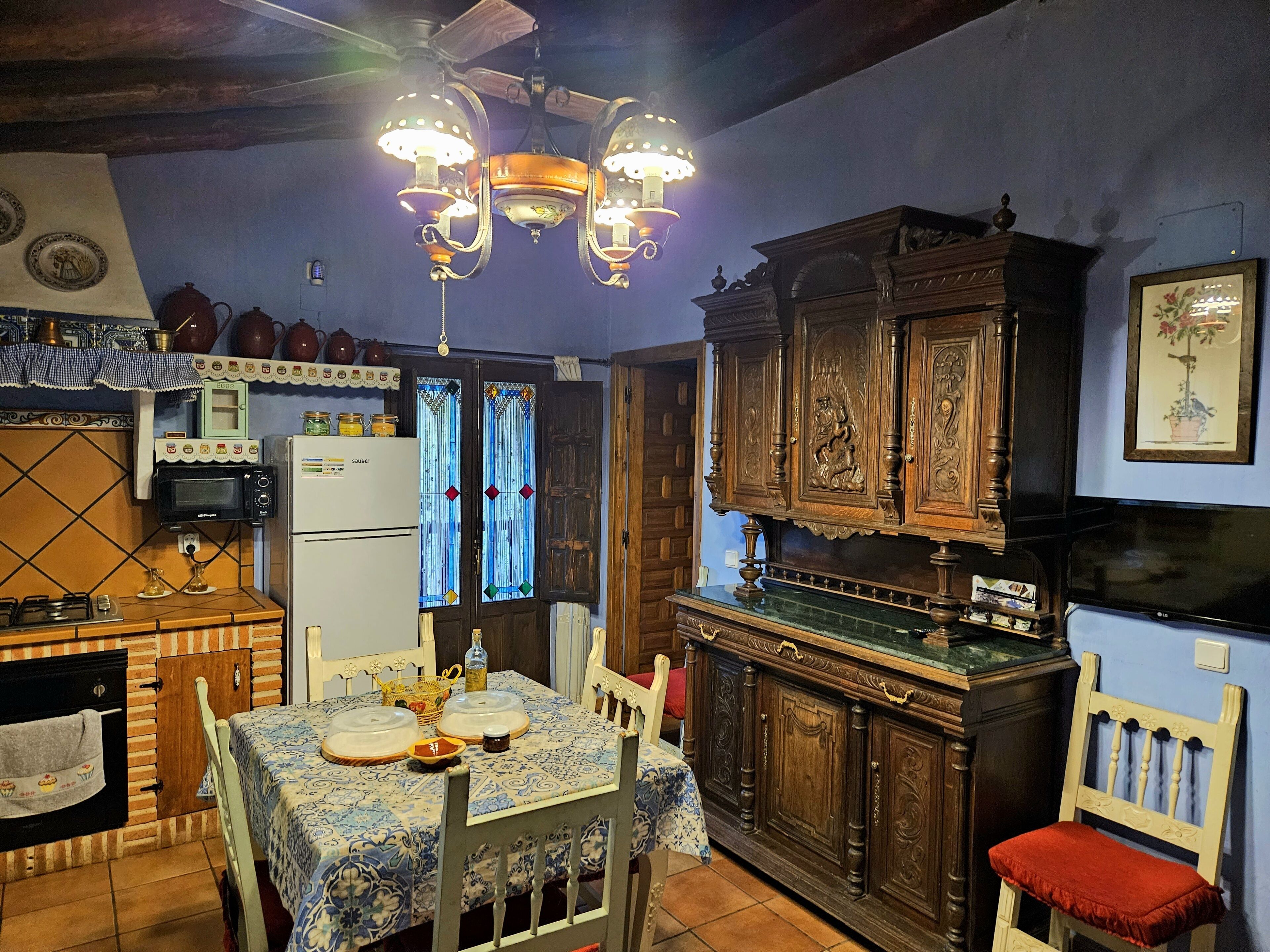 A kitchen with a dining table, chairs, a refrigerator, and a wooden cabinet.