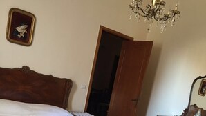 A bedroom with a large wooden bed, a wooden dresser, a chandelier, and a mirror.