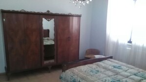 A bedroom with a bed, a wardrobe, and a mirror.