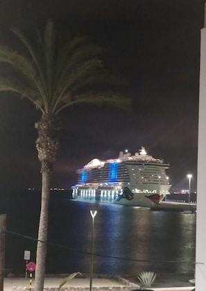 A large cruise ship docked at night with illuminated blue lights on the lower deck.
