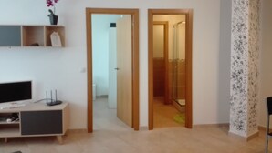 Un salon moderne avec un téléviseur à écran plat, un meuble de rangement en bois et une plante en pot.