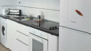 Une cuisine moderne avec des meubles blancs, un four encastré, un four à micro-ondes et un lave-linge.