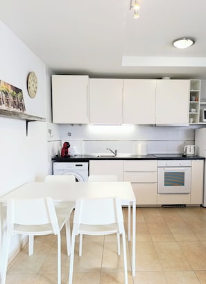 Eine moderne Küche mit weißen Schränken, einer Spüle, einem Geschirrspüler und einem Tisch mit Stühlen.