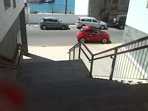 A staircase leading to a parking area with several cars parked.