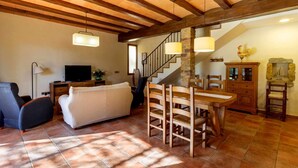A spacious living area with a wooden dining table, a sofa, and a TV. - RURAL HOUSE IN THE COSTA BRAVA (Sant Feliu De Boada)