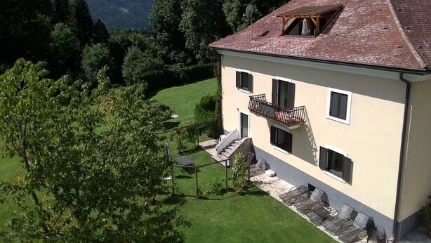 Une maison à deux étages dotée d’un balcon, d’un escalier en pierre et d’une pelouse bien entretenue.
