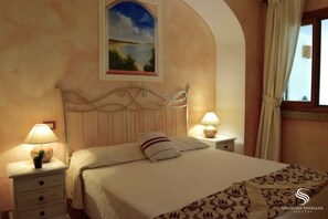 Quarto com cama, mesas de cabeceira, luminárias, um quadro e uma janela com cortinas.