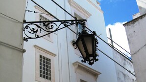 Ein weißes Gebäude mit Balkon, Fenster und einer Straßenlaterne.