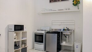 Una kitchenette compacta equipada con microondas, horno y refrigerador.