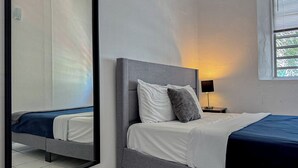 Un dormitorio con una cama, una mesita de noche, una lámpara y una ventana con persianas.