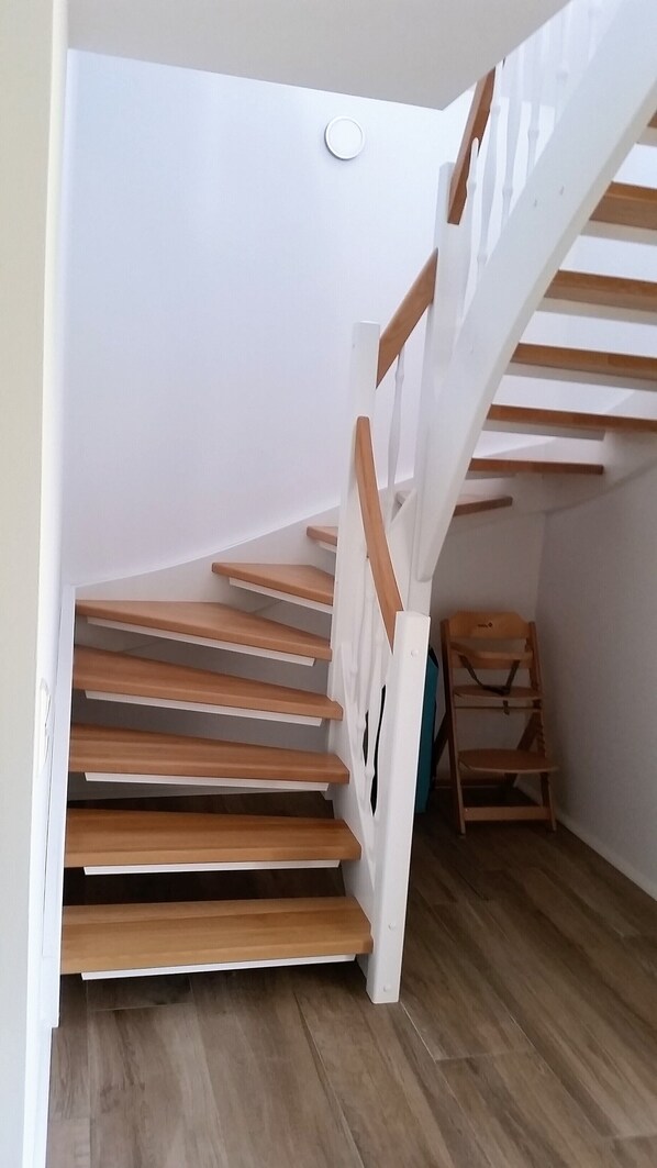 Un escalier en bois avec des rampes blanches et une chaise en bois au bas de l’escalier.