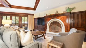 A living room with a fireplace, wooden furniture, and a television.