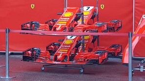 A row of red Formula 1 cars parked in a garage.