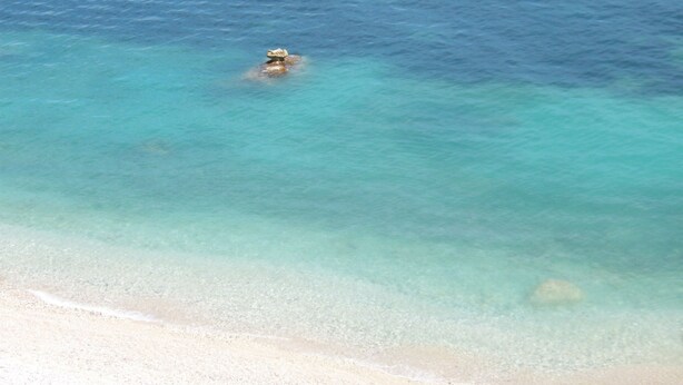 Une plage à l’eau turquoise et limpide, bordée d’un rivage sablonneux.