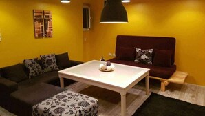 Un salon avec un canapé, une table basse et des luminaires suspendus.