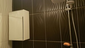 Une salle de bain avec une douche, un meuble blanc et un mur carrelé orné d’un motif ondulé.