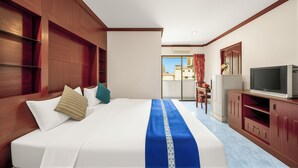 A hotel room with a large bed, a television, a dining area, and a view of the city. - Selina Place Pattaya (Pattaya)