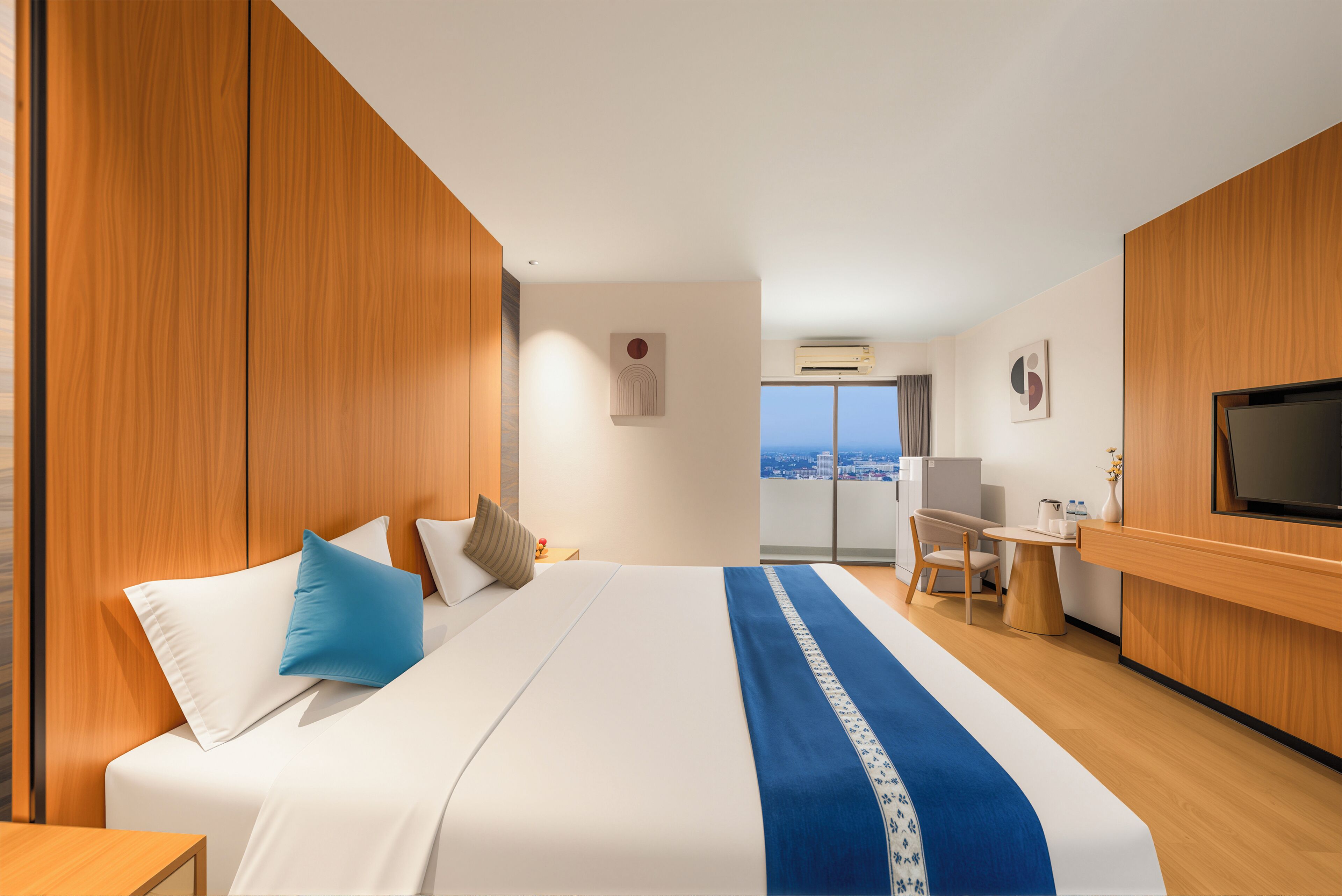 A hotel room with a bed, a desk, a television, and a view of the city.