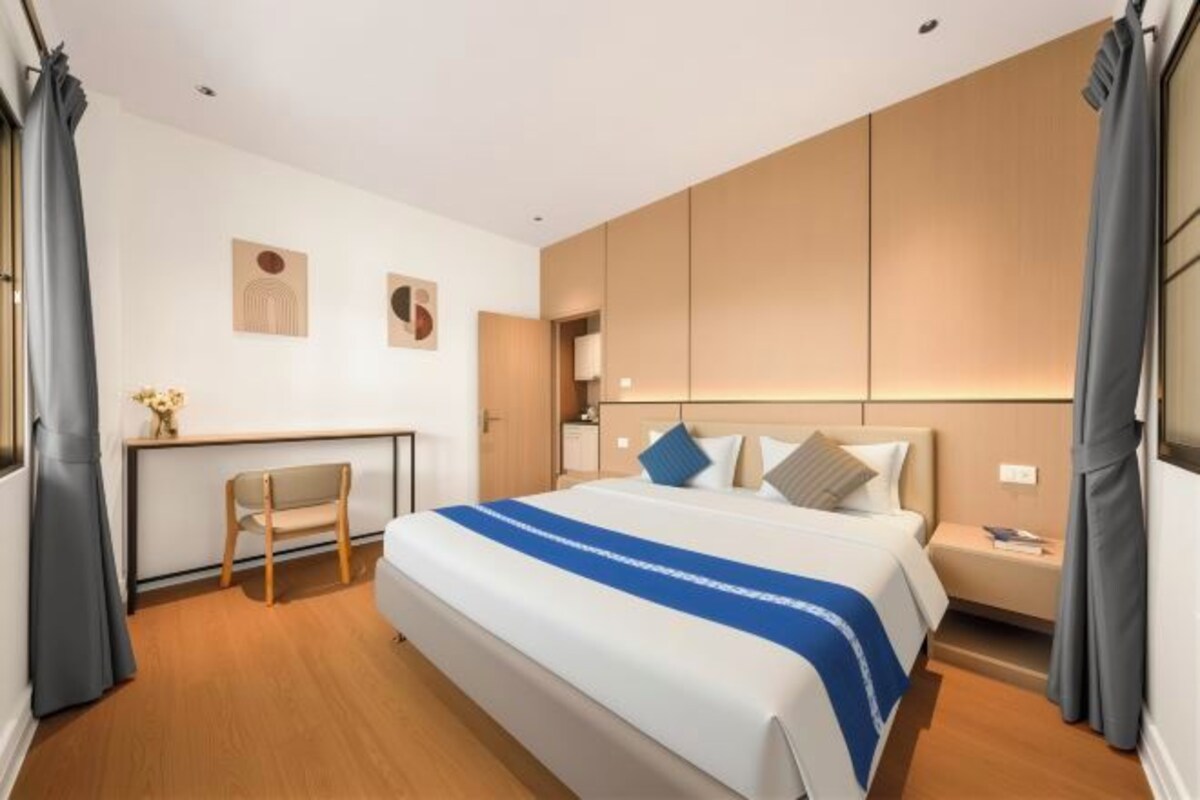 Quarto de hotel com uma cama grande, uma escrivaninha e uma cadeira.