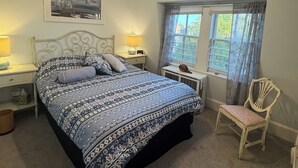A bedroom with a bed, a chair, a ceiling fan, a window, and a picture on the wall. - Cozy 2 BR Apt in historic Cape May, NJ (Cape May)