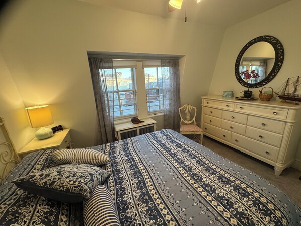 Une chambre à coucher avec un lit, une commode, une chaise, une fenêtre et un miroir.