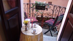 Une petite table ronde recouverte d’une nappe, avec une bougie, un vase de fleurs, ainsi que deux tasses et leurs soucoupes.