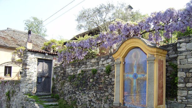 Un mur de pierre avec un petit escalier menant à une porte, et un bâtiment avec une porte jaune et bleue.