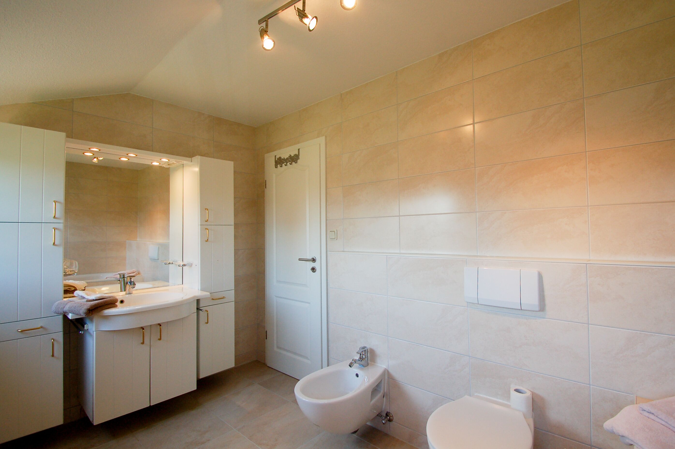 Ein modernes Badezimmer mit Waschbecken, Bidet, Toilette und Spiegel.