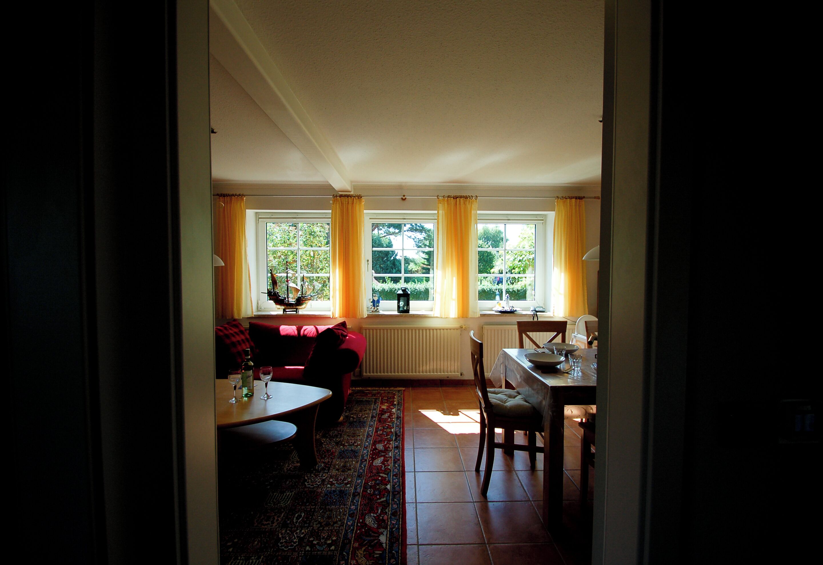A room with a dining table, a sofa, and a window with curtains.
