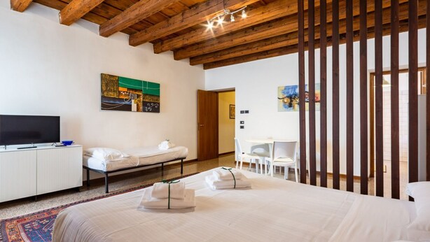 Una habitación de hotel con una cama grande, televisión, escritorio y una silla.