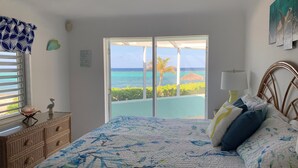 Una camera da letto con un letto, una cassettiera, una finestra vista oceano e una ventola a soffitto.