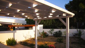 Eine weiße Pergola inmitten eines Gartens unter blauem Himmel.