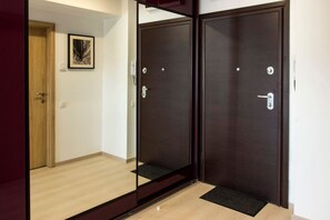 A hallway with a wooden door, a framed picture on the wall, and a dark wooden door with a handle.