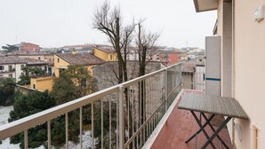 Ein Balkon mit Blick auf eine Stadtlandschaft, darunter Gebäude und Bäume.